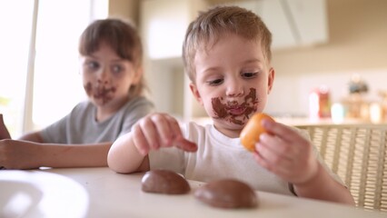 children eat chocolate. dirty little baby kids in the kitchen eating chocolate in the morning. happy family eating sweets kid dream concept. baby dirty face eating chocolate cocoa lifestyle