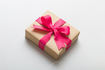 Wrapped christmas or other holiday handmade present in craft paper with colored ribbon. Present box, decoration of gift on table, top view with copy space