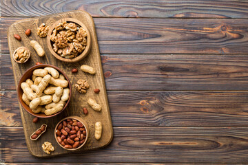 Walnut kernel halves with peanut, in a wooden bowl. Close-up, from above on colored background. Healthy eating groundnut concept. Super foods with copy space