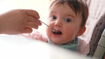 grimy baby eats from a spoon close-up. happy family kid dream concept. dirty baby close-up eats with a spoon. baby opens mouth eats mashed potatoes from a lifestyle spoon