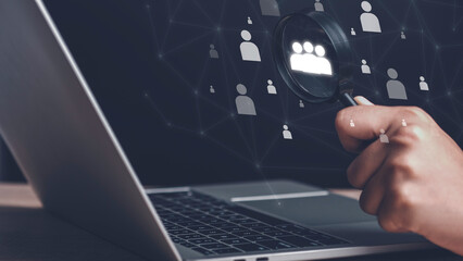 Human Resource Management and Customer Relationship Management concept. Hand holding magnifying glass with human icon for focus customer target for human development recruitment leader.