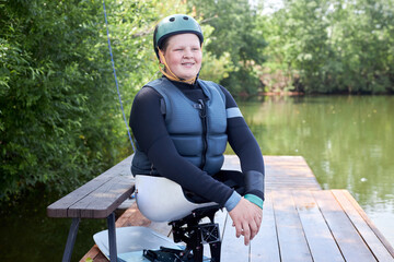 Portrait of smiling young man with disability using adaptive sports equipment and helmet while...