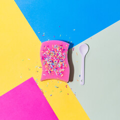 Pink sponge for dishes in the form of a birthday cake with sprinkles on multicolor background. Flat lay - 640221181