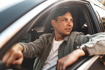 Young smiling man sitting in a car with open window