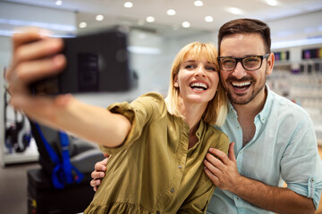 Smiling couple have fun using smartphone, watch video on cellphone make self-portrait picture