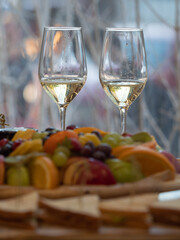 Two glasses of white wine with fruit and sandwiches in the foreground