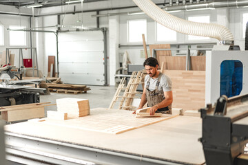 Fototapeta na wymiar Young man doing woodwork in carpentry factory