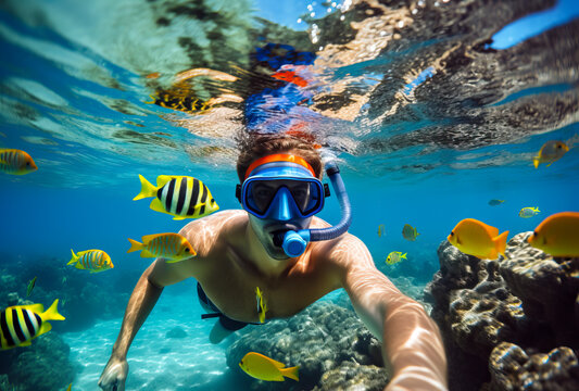 Man snorkeling in the tropical water with colorful fishes and corals. Shallow field of view