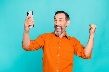 Photo of funny senior businessman brunet hair recording video phone selfie fist up holding phone lottery isolated on blue color background