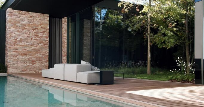Terrace with swimming pool and comfortable sofa on backyard of modern cottage house. Vacation and rest concept