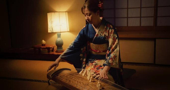 Portrait of a Female Playing on a Japanese Koto. Woman Wearing a Blue Kimono with Colorful Flower Ornaments, Skilfully Using Her Fingers on a Traditional String Instrument