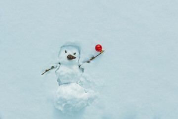 Snowman with red Christmas ball on branch in snow