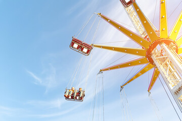 Scenic bottom view high chain swing flying carousel against blue sky. Merry go round roundabout chairoplane at portable amusement park. People enjoy having family fun play riding at fair festival © Kyryl Gorlov