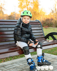 The boy is resting after roller skating. wearing a black jacket with a green helmet on his head