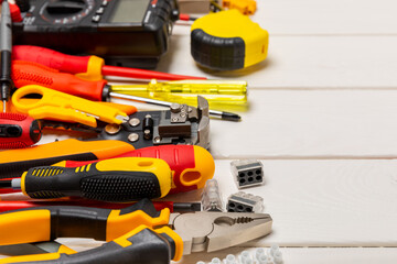 Electrician equipment on a wooden background with copy space.Top view.Electrician tool set.Multimeter, tester,screwdrivers,cutters,duct tape,lamps,tape measure and wires.Flet lay.Concept building © Avocado_studio