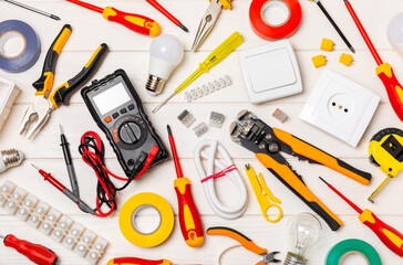Electrician equipment on a wooden background with copy space.Top view.Electrician tool set.Multimeter, tester,screwdrivers,cutters,duct tape,lamps,tape measure and wires.Flet lay.Concept building