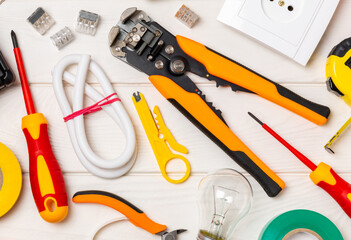 Electrician equipment on a wooden background with copy space.Top view.Electrician tool set.Multimeter, tester,screwdrivers,cutters,duct tape,lamps,tape measure and wires.Flet lay.Concept building © Avocado_studio