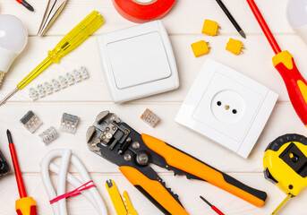 Electrician equipment on a wooden background with copy space.Top view.Electrician tool set.Multimeter, tester,screwdrivers,cutters,duct tape,lamps,tape measure and wires.Flet lay.Concept building © Avocado_studio
