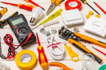 Electrician equipment on a wooden background with copy space.Top view.Electrician tool set.Multimeter, tester,screwdrivers,cutters,duct tape,lamps,tape measure and wires.Flet lay.Concept building © Avocado_studio