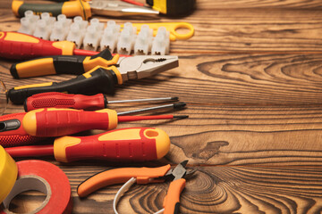 Electrician equipment on a wooden background with copy space.Top view.Electrician tool set.Multimeter, tester,screwdrivers,cutters,duct tape,lamps,tape measure and wires.Flet lay.Concept building © Avocado_studio