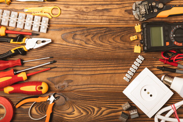 Electrician equipment on a wooden background with copy space.Top view.Electrician tool set.Multimeter, tester,screwdrivers,cutters,duct tape,lamps,tape measure and wires.Flet lay.Concept building © Avocado_studio