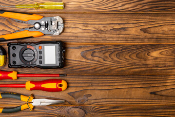 Electrician equipment on a wooden background with copy space.Top view.Electrician tool set.Multimeter, tester,screwdrivers,cutters,duct tape,lamps,tape measure and wires.Flet lay.Concept building © Avocado_studio