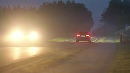 Passenger Car Driving Countryside Road Covered in Dense Fog After Sunset