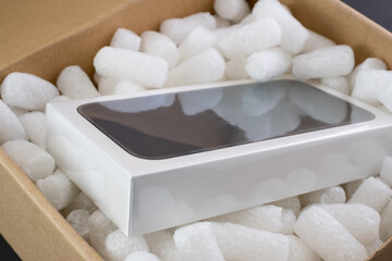 Packing Care peanuts in a cardboard box with a new device, protective granules. Online shopping.