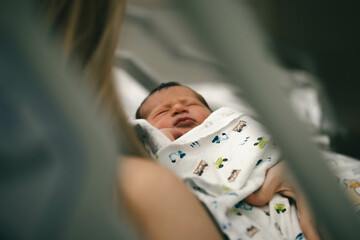  newborn baby rests peacefully in a woman's arms in a hospital's bed