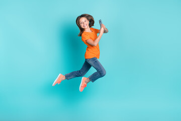 Fototapeta na wymiar Photo of optimistic crazy girl wear trendy orange outfit hurry store mall buy modern device isolated on cyan color background
