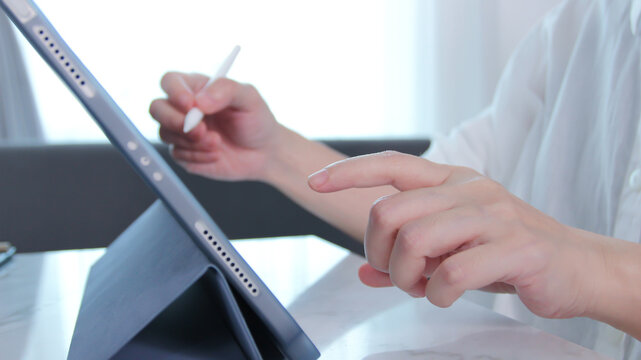 Closeup of woman hand hold electronic pen and writing on digital tablet for searching on web page, technology, website, Business and technology concept. Working with tech device.