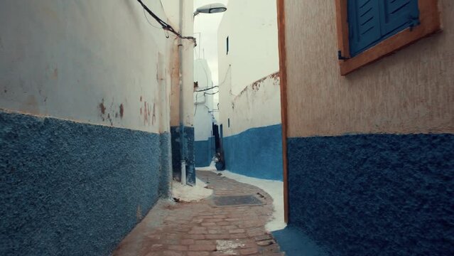 Walking through narrow street in Old Medina in Chefchaouen city Morocco. Blue and white wall houses.