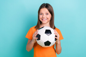 Portrait of good mood schoolgirl with straight hair dressed orange t-shirt hands hold soccer ball...