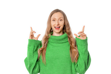 Portrait of blonde woman pointing fingers up, showing advertisement on top, recommending click on link, demonstrating promo banner, wearing green cozy sweater, standing over white background
