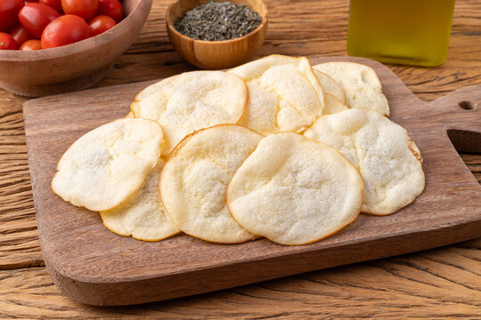 Smoked provolone cheese chips in a bowl with cherry tomatoes and oregano over wooden table