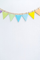 Fabric colorful bunting flag with space on white cement wall background, vertical style, festive background idea