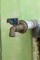 Old faucet on green wall background, closeup of photo