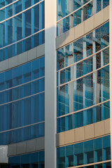 Close up of modern office building with blue glass facade and sunlight.