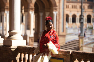 Young black woman dressed as a flamenco gypsy in a famous square in Seville, Spain. She wears a...