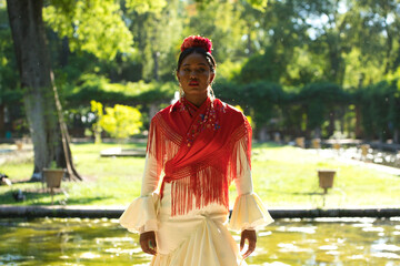 Young black woman dressed as a flamenco dancer stands in a famous park next to a duck pond in...