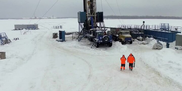 Workers is going to station with pipe and valve. Testing center at mineral oil depot or tank farm. Outdoor powerful production area or facility. Distiller of crude. Well for gas, gasoline. 