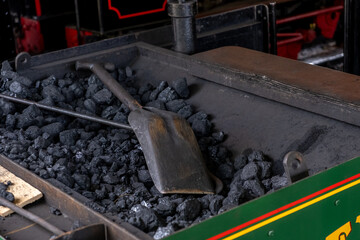 Bressingham, Norfolk, UK – August 21 2023. Coal scuttle on a pile of coals on a steam train