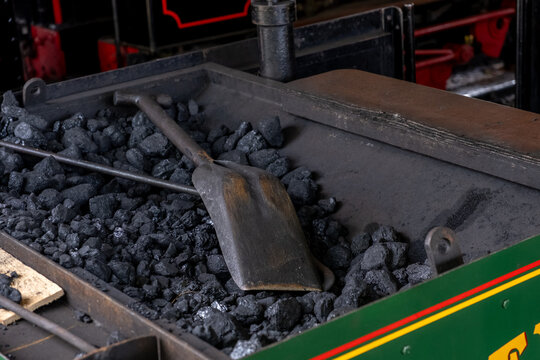 Bressingham, Norfolk, UK – August 21 2023. Coal scuttle on a pile of coals on a steam train