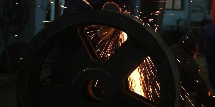 Male hand cuts off pieces of water pipe with angle grinder. Sparks during cutting of metal angle grinder