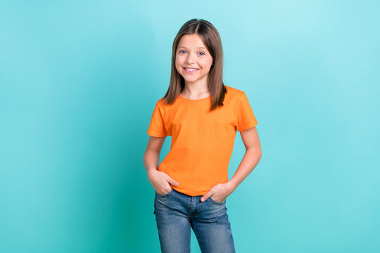 Portrait Of Funny Small Girl Wearing Orange T-shirt Blue Jeans Standing Confident Advertising Outift Isolated Cyan Color Background