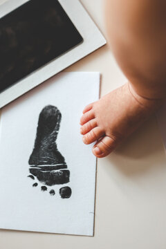 Baby footprints on white paper. Black footprint. The process of creating a baby footprint