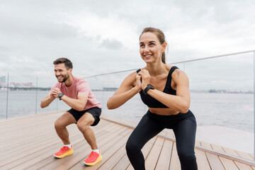 The trainer and the client teach fitness exercises. Confident, strong people in sportswear. A couple of friends are using a fitness watch and a sports app.  A man and a woman train together.