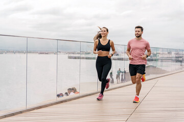 People in sportswear and sneakers are doing sports. The trainer uses a fitness watch. A man and a woman train together. Friends do physical exercises in the fresh air for the body.