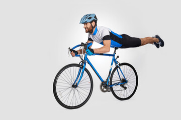 Strong middle aged cyclist doing trick on bike, while riding. Side view of caucasian male rider cyclist showing acrobatic stunt, isolated on white background. Cycling skills, sport activity concept.