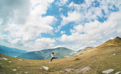 The desire to fly, to be free. A beautiful young woman runs in a spectacular mountain landscape.